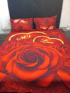 A bed with a red rose design and the words 'My Love' on the bedspread.