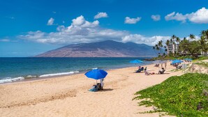 A beach with a mountain in the background, palm trees, and a clear blue sky. - Budget Friendly - Kihei Akahi C-608, Ocean Views, Short Walk to Kamaole Beach II (Kihei)