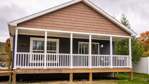 A two-story house with a covered porch and a small deck. - The Leland Blue on M-22 (Suttons Bay)