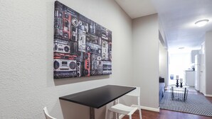 Una cocina moderna con encimera negra, sillas blancas y un cuadro abstracto grande en la pared.