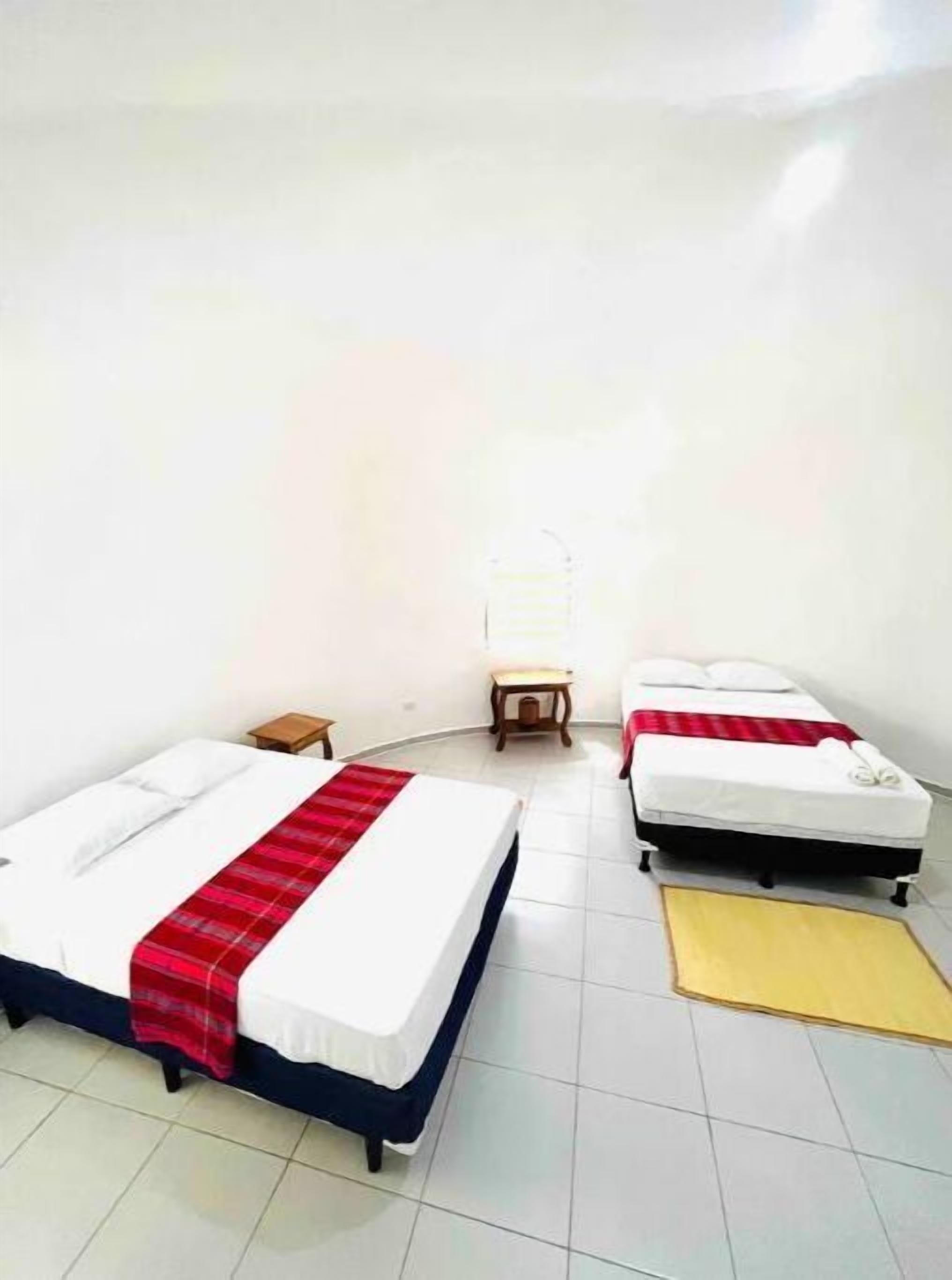 Une chambre avec deux lits, une petite table et une chaise.