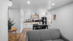 A compact living space with a kitchenette, a dining area, and a seating area. - Riverside Suite | Kitchenette, Firepit & BBQ (Lake Cowichan)