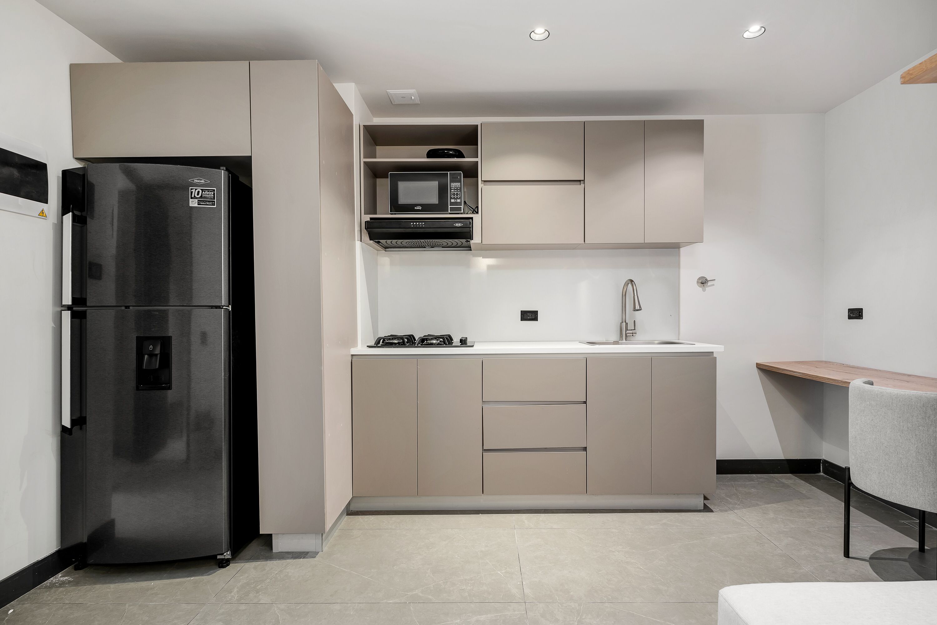 A modern kitchen with a stainless steel refrigerator, a microwave, and a sink.