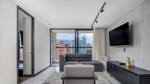 Un salon moderne avec un canapé, un pouf et un téléviseur à écran plat fixé au mur.