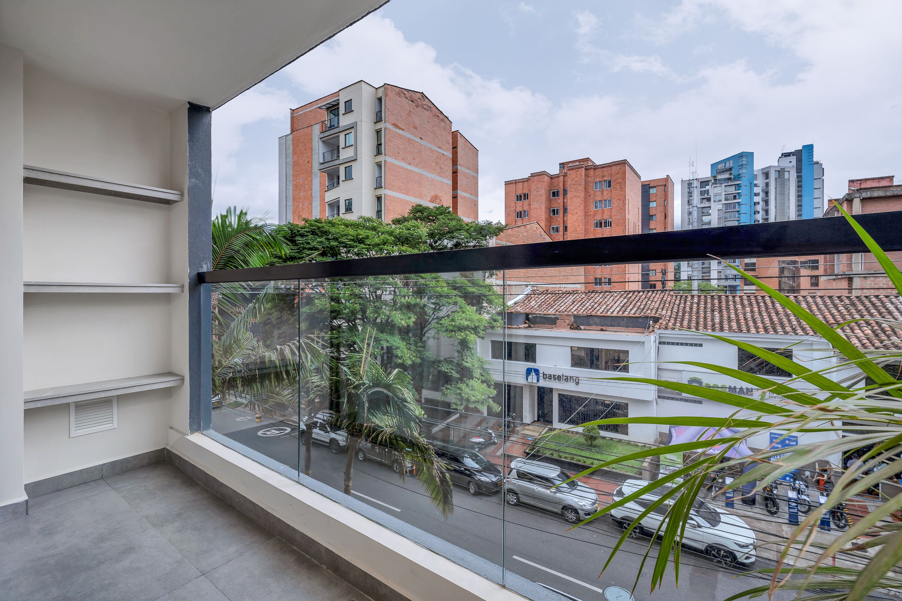 A balcony with a view of a cityscape, including a building with the sign 'Baselung'.