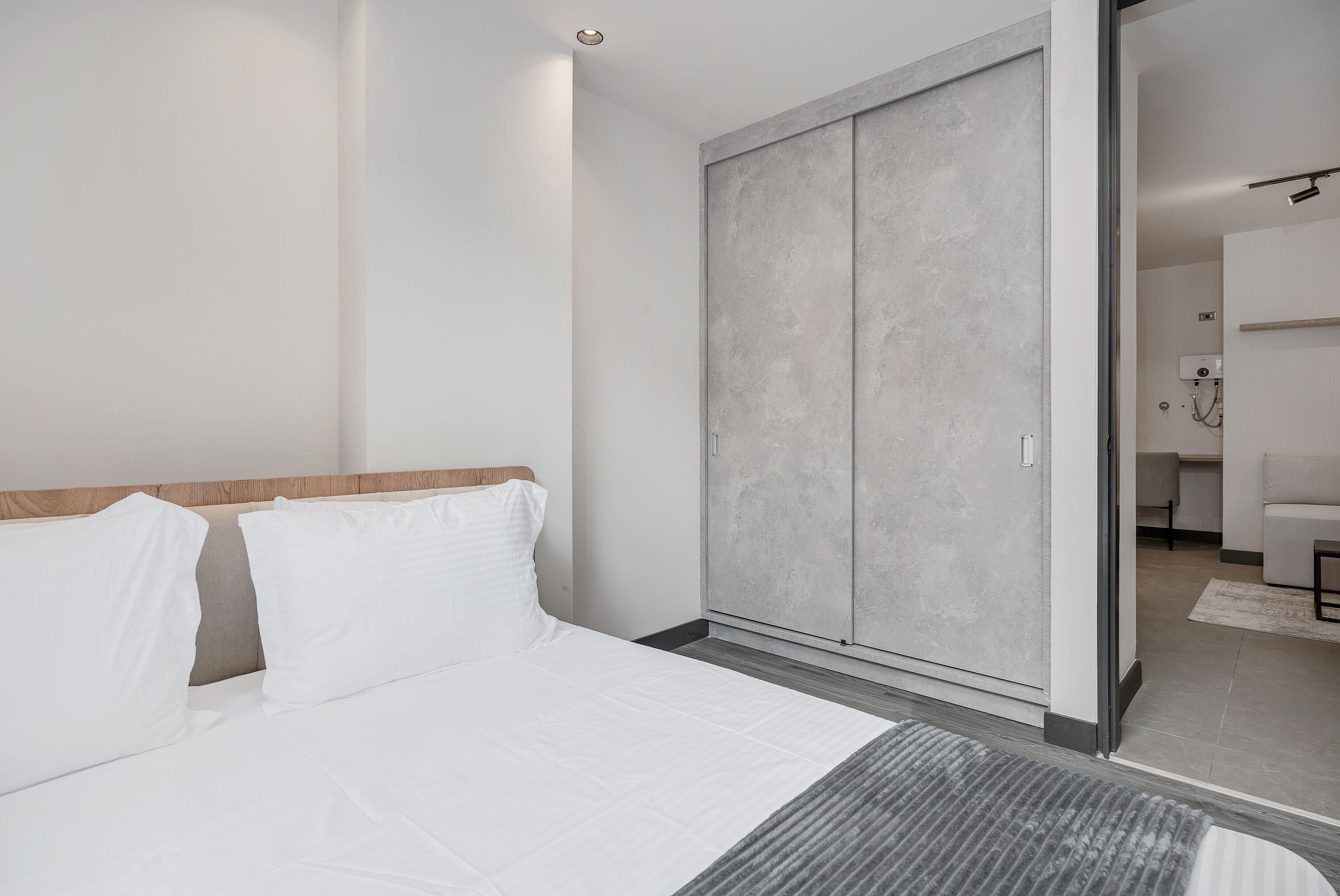 Une chambre moderne avec un grand lit, une armoire grise et une tête de lit en bois.