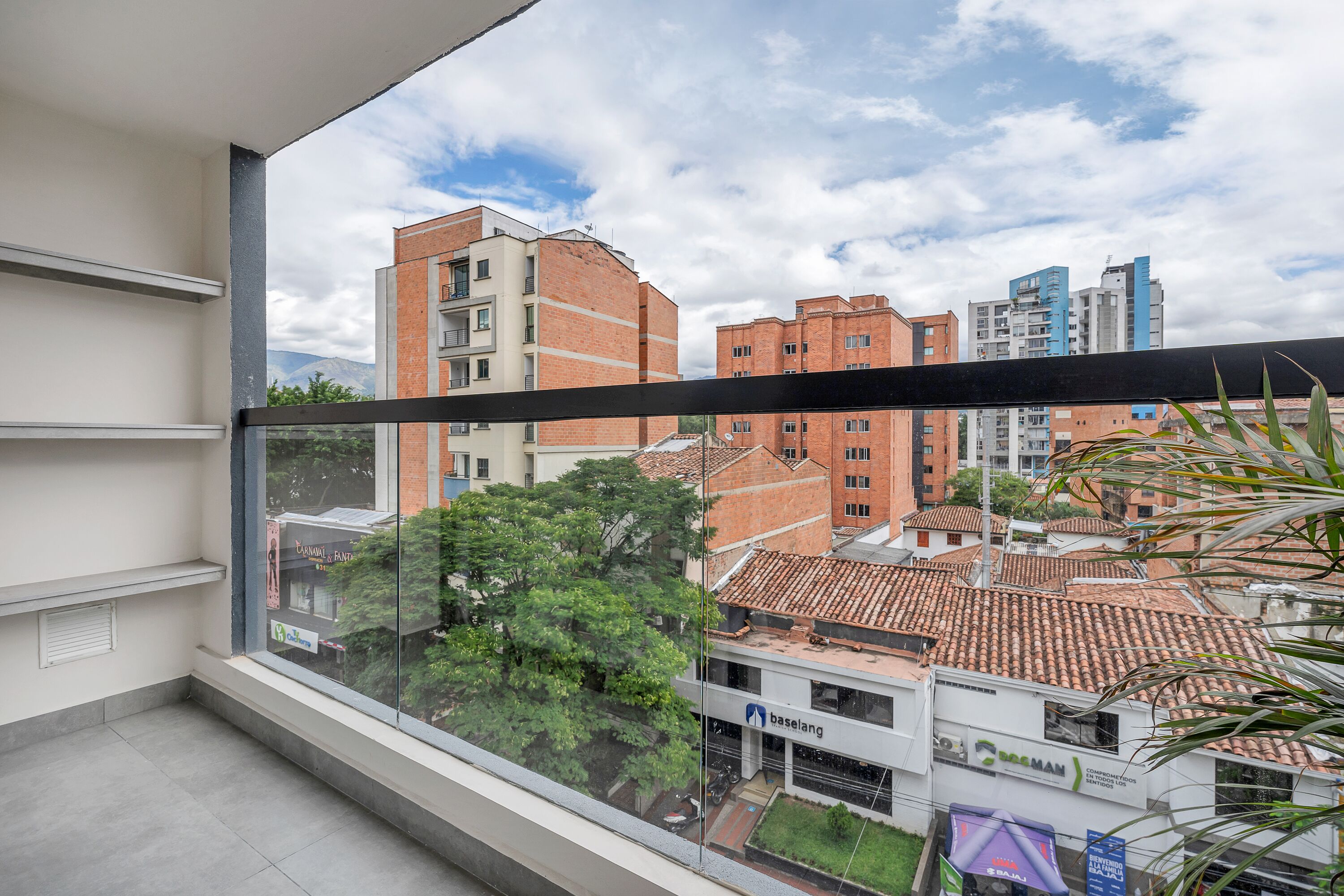 A balcony with a view of a cityscape, including buildings and a tree.