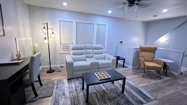 A modern living room with a sofa, armchairs, a coffee table, and a desk.