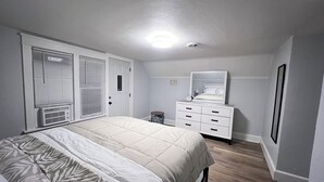 A bedroom with a bed, dresser, and a mirror.