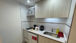 Una cocina compacta equipada con microondas, tostadora, cafetera y lavabo.
