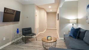 Una sala de estar moderna con un sofá, una mesa de centro, una silla y un televisor montado en la pared.