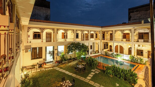 Um pátio com piscina, área de estar externa e jardim.