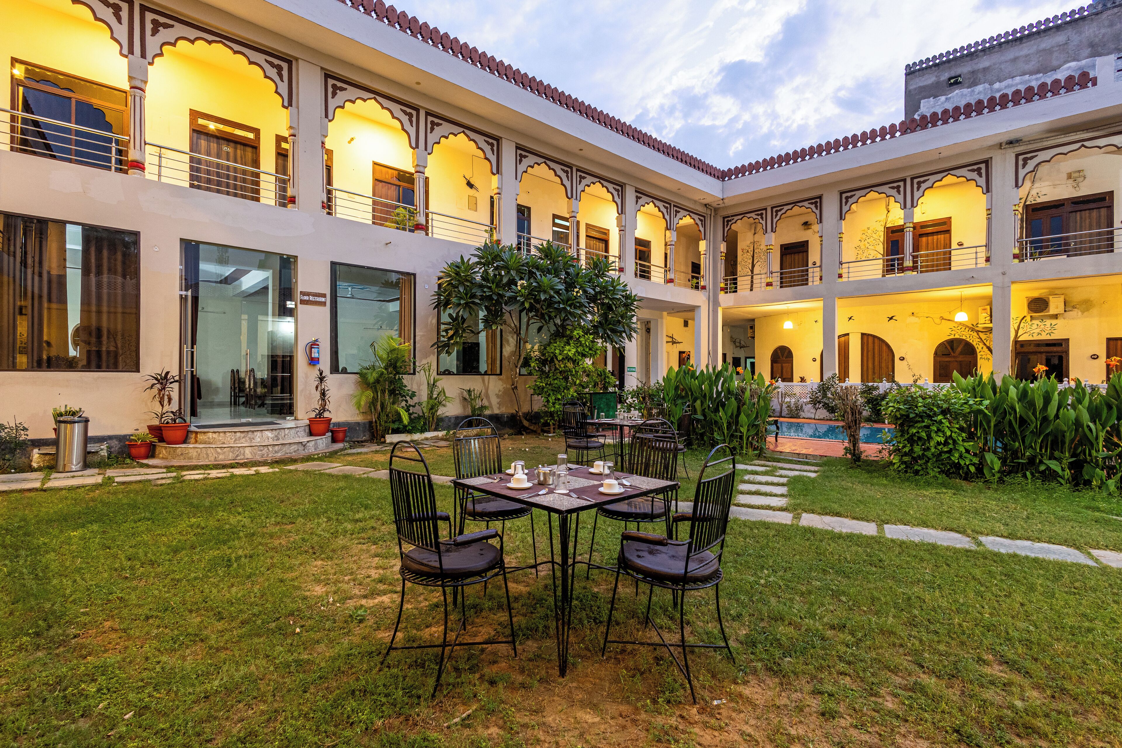 A courtyard with a dining area, potted plants, and a pool.