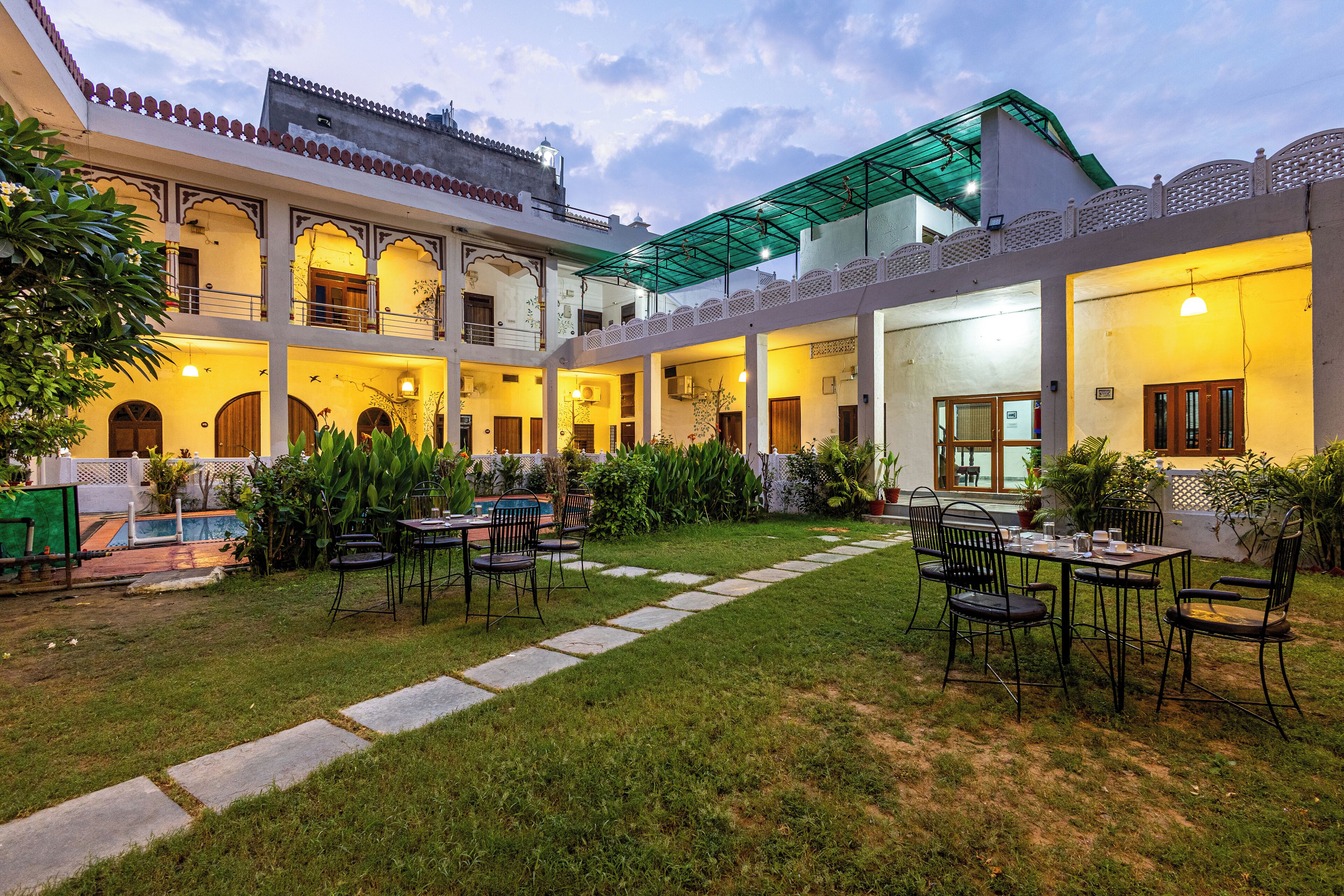 A courtyard with a pool, outdoor seating, and a covered area with a green roof.
