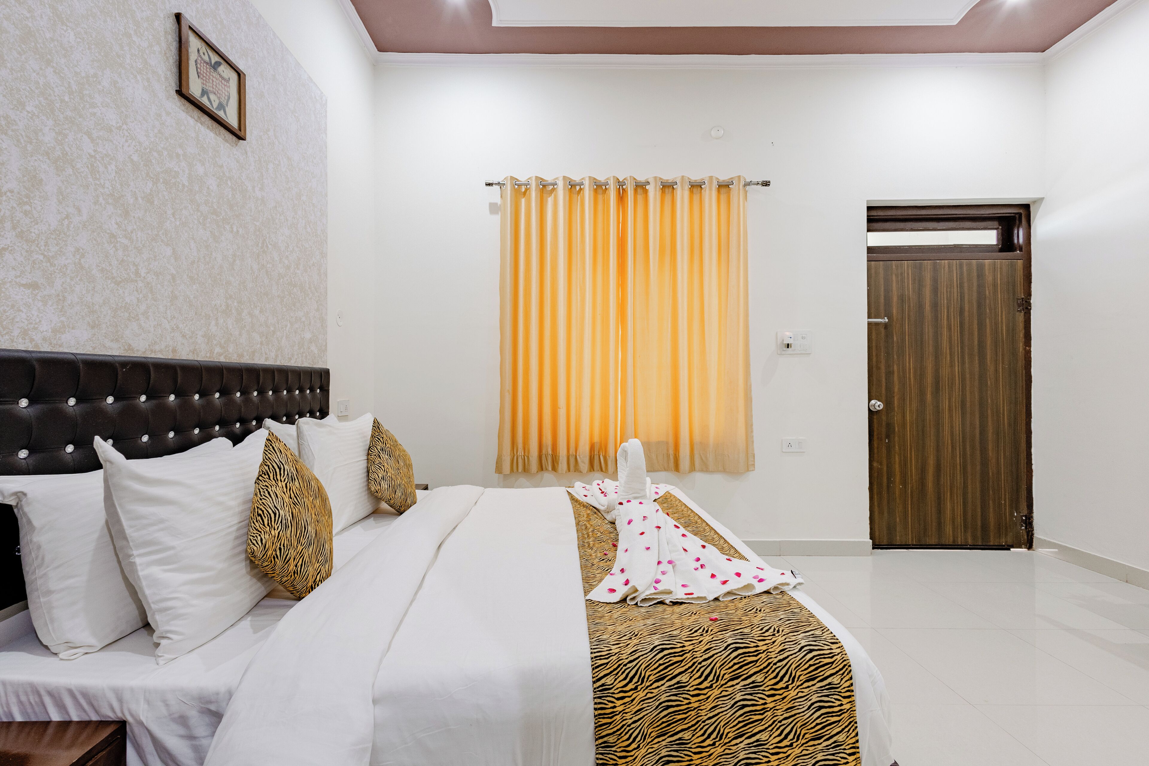 A hotel room with a bed, a headboard, a curtain, and a door.