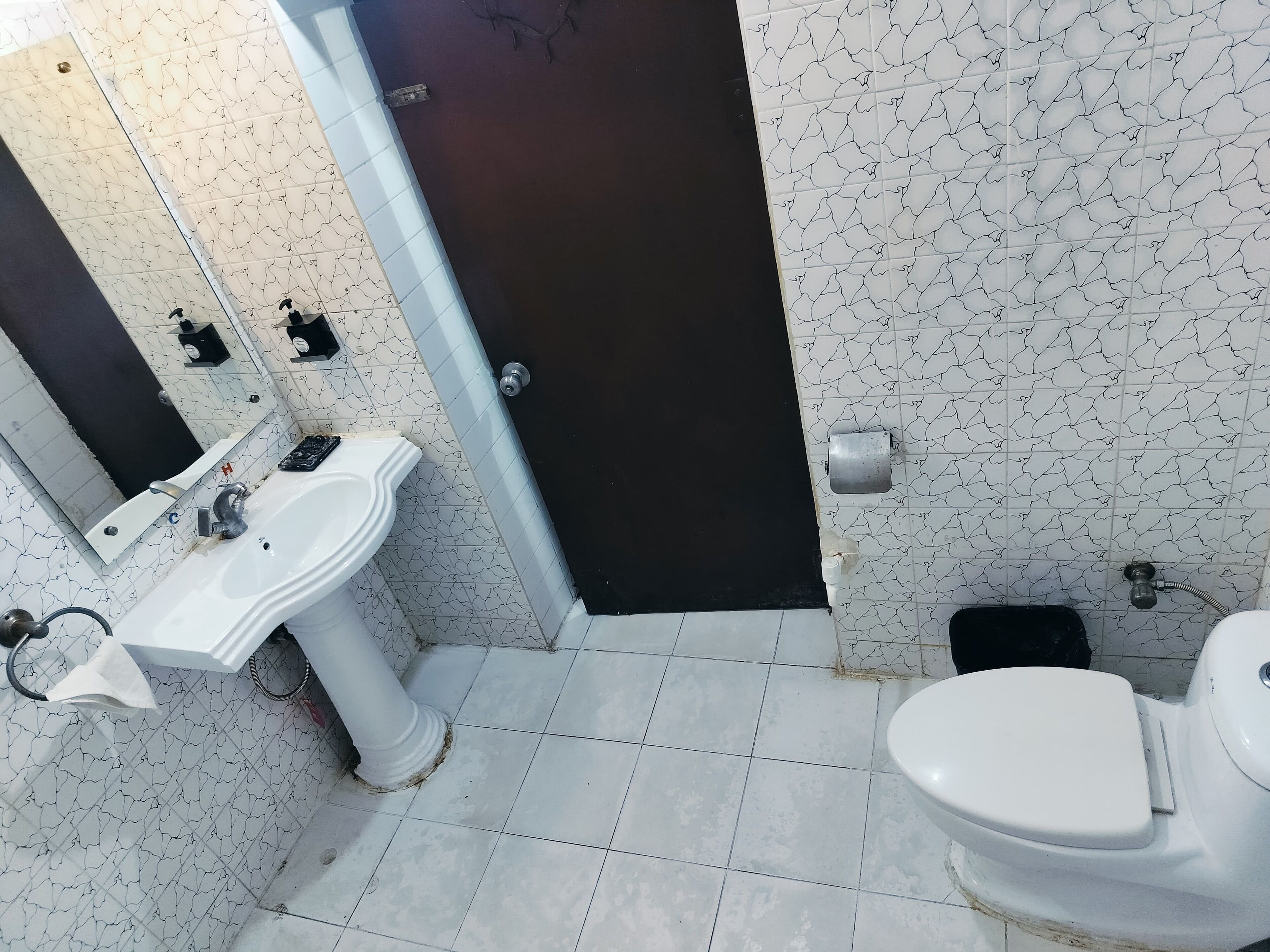 Ein Badezimmer mit einem weißen Waschbecken, einer Toilette und einer dunklen Tür.