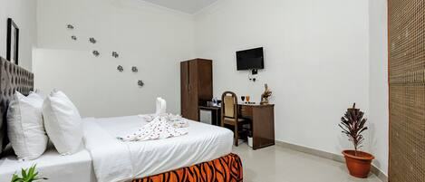 Una habitación de hotel con cama, escritorio, televisor y una planta en maceta.
