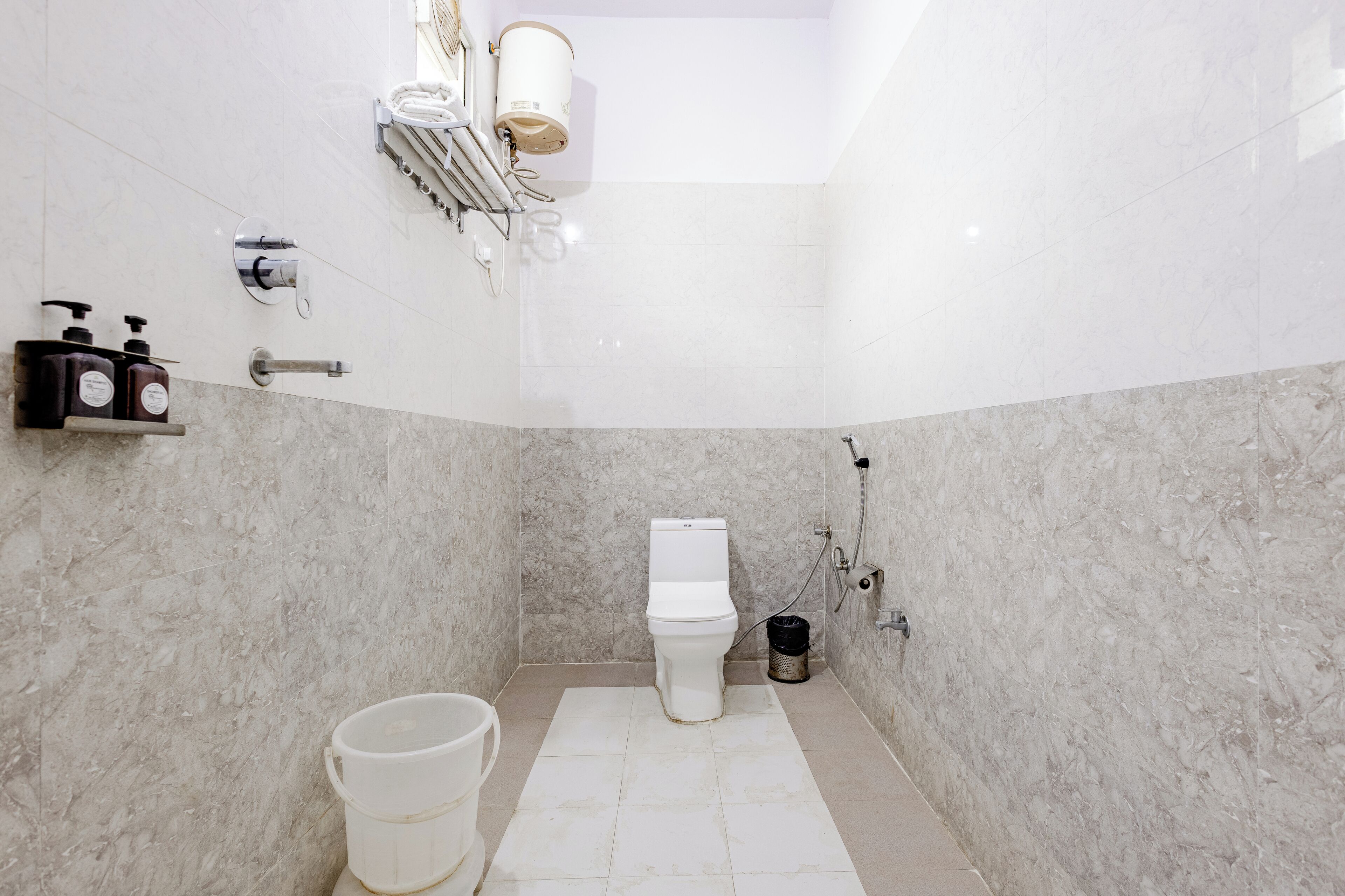 Un baño con inodoro, ducha, lavamanos y un estante con artículos de aseo.