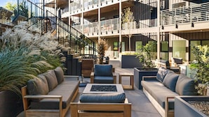 An outdoor seating area with wooden furniture and planters, a staircase, and a modern building with balconies. - The Speakeasy- Walk to Broadway! Pool, Gym, Parking & More, Amazing Location (Nashville)