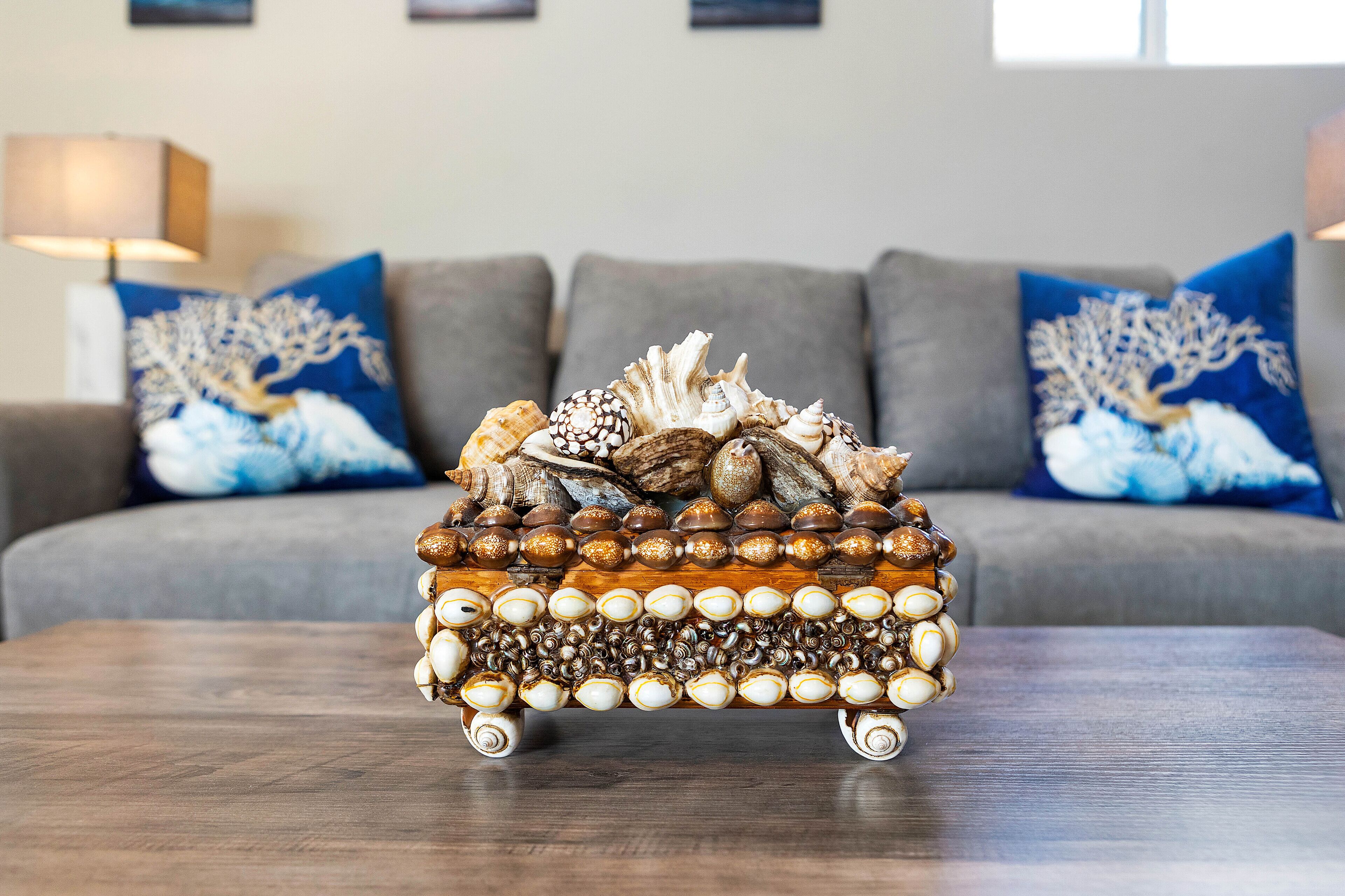 A decorative wooden table with a unique arrangement of seashells and beads.