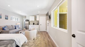 A compact living space with a kitchenette, a sofa, a bed, and a dining area.