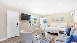 A modern living room with a sofa, armchairs, a coffee table, and a flat-screen TV mounted on the wall.