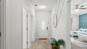 Un pasillo con una puerta blanca, un banco y una planta en maceta.