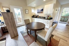 A modern kitchen with white cabinets, a round dining table, and a view of the outdoors.