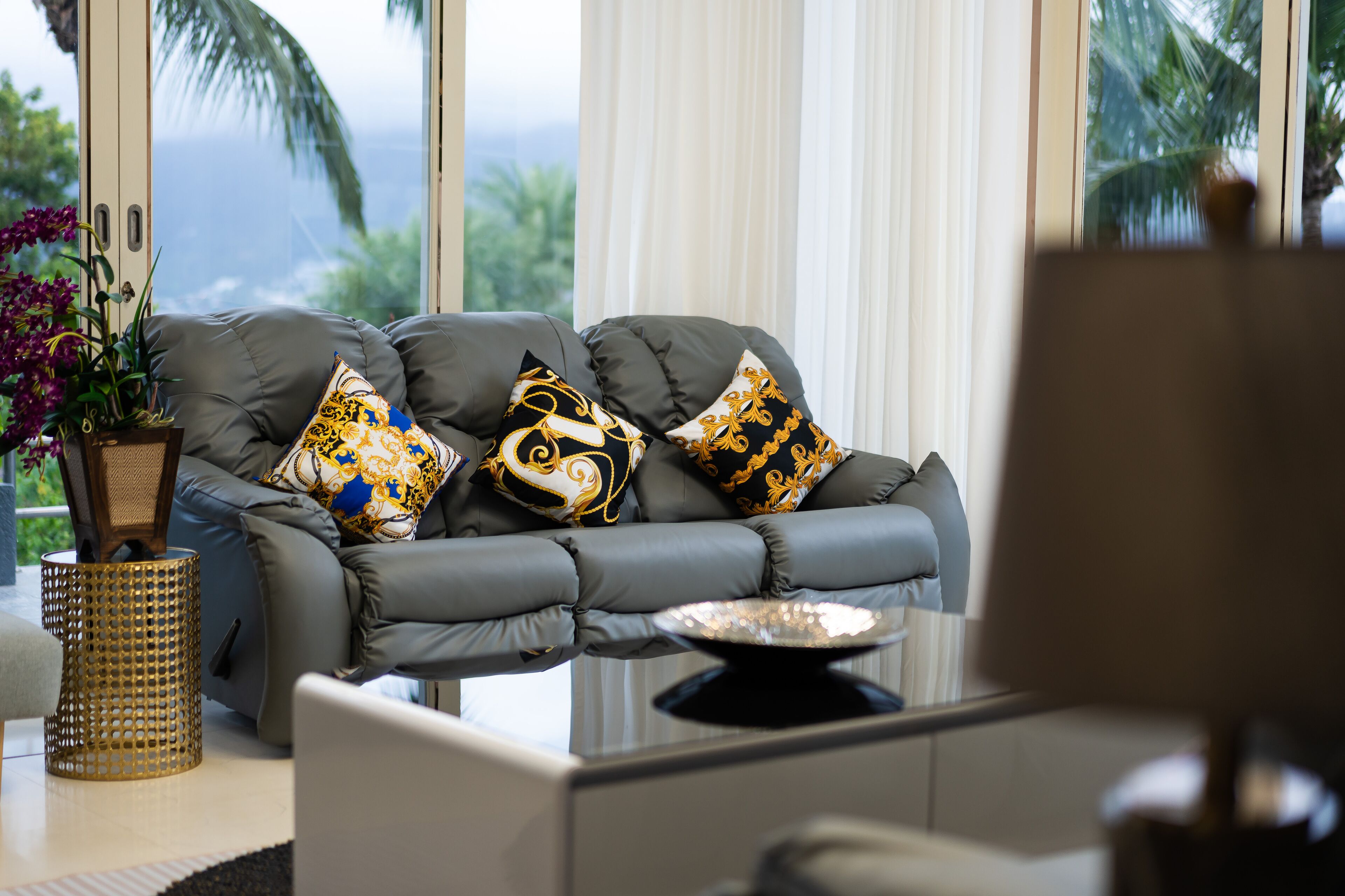 A modern living room with a grey sofa, decorative pillows, a small table, and a potted plant.