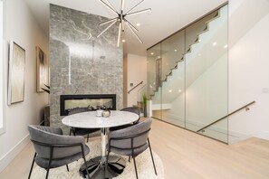 Uma área de refeições moderna com parede de mármore, uma mesa redonda e quatro cadeiras.