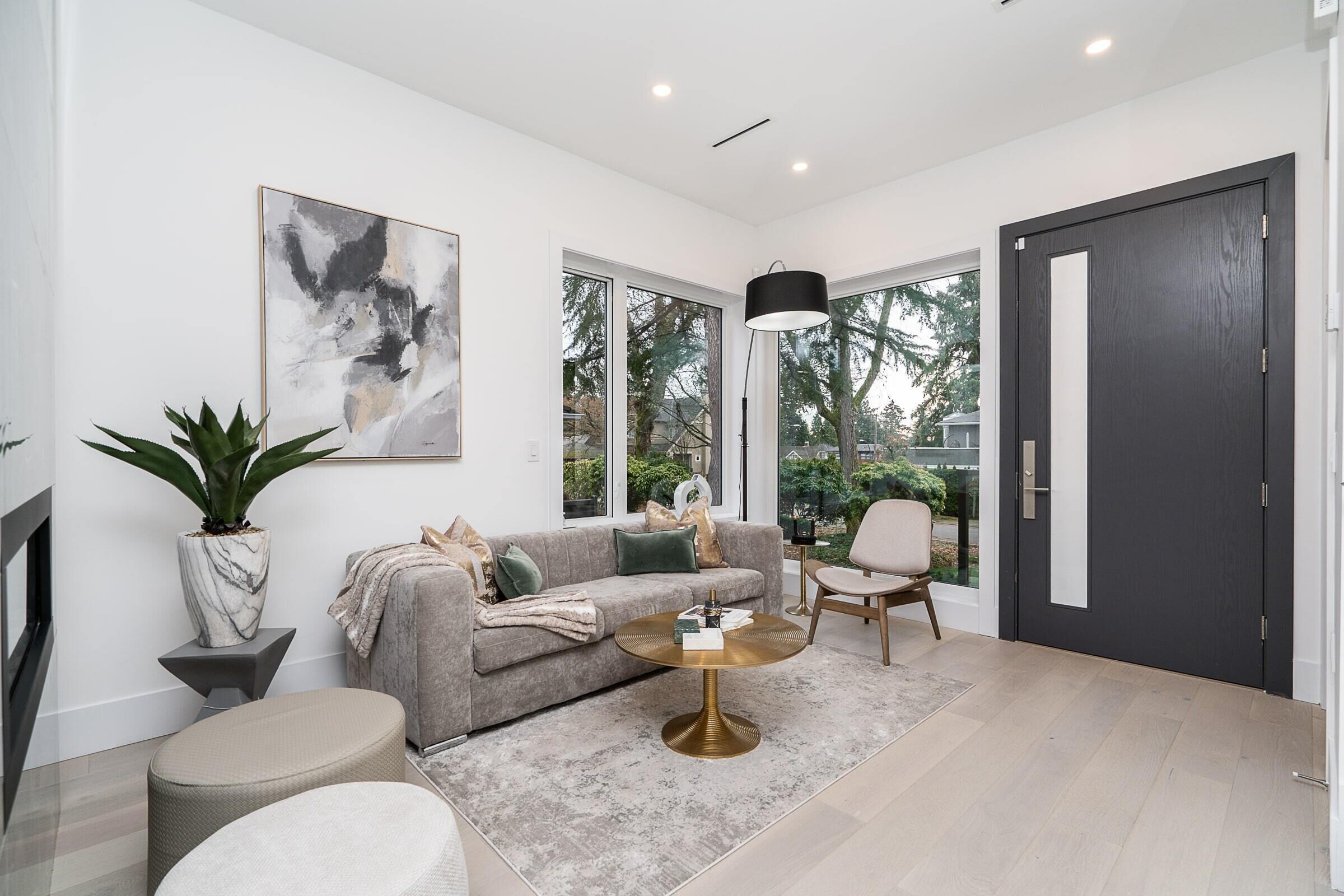 A modern living room with a grey sofa, a round coffee table, and a large abstract painting on the wall.