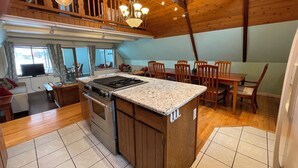 Cocina con isla central, mesa de comedor de madera y sillas.