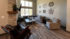 A spacious living room with a stone accent wall, a large window, and a variety of decorative wall art. - Beautiful 3-bedroom townhome at Purgatory Resort with mountain views, perfect for families. (Durango)