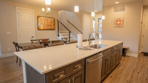 A modern kitchen with a large island, stainless steel appliances, and pendant lighting.