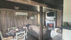 A dining area with a wooden table and white chairs, a sofa, and a fireplace.
