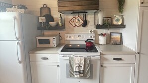 A kitchen with a white stove, oven, and refrigerator. There is a wooden ceiling and a stone tile floor.