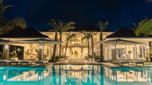 Un resort lujoso con piscina, mobiliario exterior y una entrada bien iluminada.