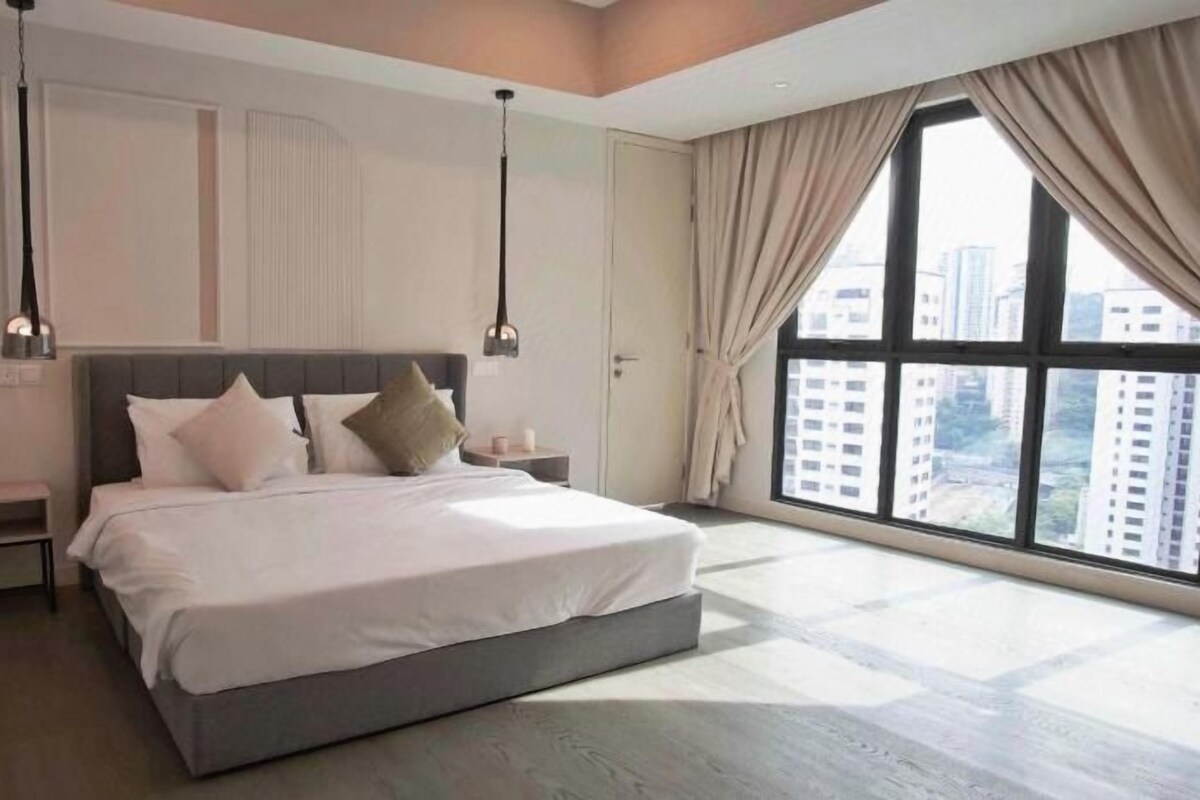 Un dormitorio moderno con una cama grande, mesitas de noche y vistas a la ciudad a través de amplias ventanas.