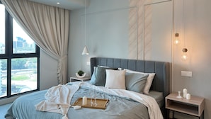 Une chambre moderne avec un grand lit, un ventilateur de plafond, une table de chevet avec une lampe et une vue sur la ville par la fenêtre.