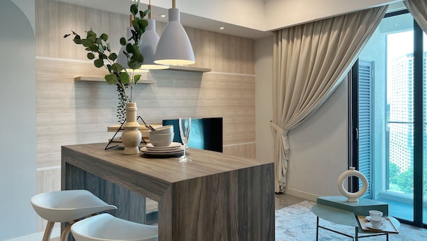 Une cuisine moderne avec un îlot central en bois, des luminaires suspendus et un coin repas avec des chaises blanches.