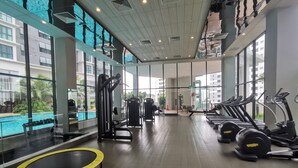 Une salle de sport équipée de matériel d’exercice, d’un trampoline et offrant une vue sur une piscine.