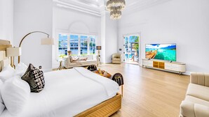 Ein geräumiges Schlafzimmer mit einem großen Bett, einem Fernseher und Meerblick durch das Fenster.