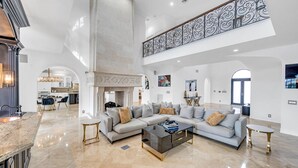 A spacious living area with a large sectional sofa, a coffee table, and a high ceiling with decorative railings.