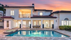 A two-story house with a swimming pool, outdoor seating, and a balcony.