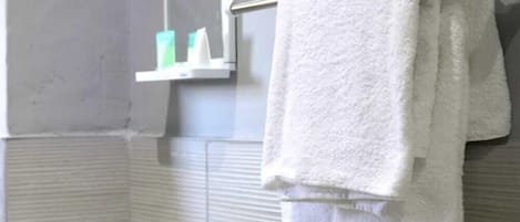 Un baño con un lavabo blanco, un toallero con una toalla blanca y un espejo.