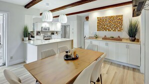 A modern kitchen with white cabinets, a wooden island, and pendant lighting. - Riviera Oasis: Waterfront, Pool, 5min To Beach (Fort Lauderdale)