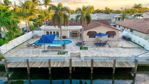 A waterfront property with a swimming pool, deck chairs, and a covered patio area. - Riviera Oasis: Waterfront, Pool, 5min To Beach (Fort Lauderdale)