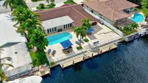 A waterfront property with a swimming pool, a dock, and a covered patio area. - Riviera Oasis: Waterfront, Pool, 5min To Beach (Fort Lauderdale)