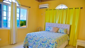 Un dormitorio con cama, ventana con cortinas, aire acondicionado y vistas al exterior.