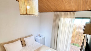 Een slaapkamer met een groot bed, een nachtkastje, een hanglamp en uitzicht op de omgeving.